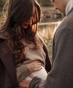 a man and woman standing next to each other holding their pregnant baby bump in the belly