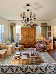 a living room filled with lots of furniture and a chandelier hanging from the ceiling