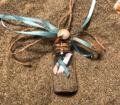 a message in a bottle is tied up on the sand with a blue ribbon around it