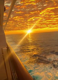 the sun is setting over the ocean as seen from a ship's bow end