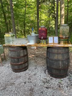 two wine barrels sitting on top of a wooden table in the middle of a forest