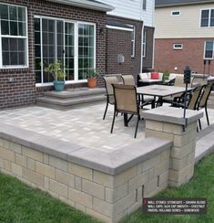 a patio with chairs and tables in front of a brick wall that has steps leading up to it