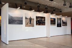 an empty room with several pictures on the wall and lights hanging from the ceiling above