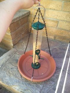 a bird feeder that is being held by someone's hand over the top of it