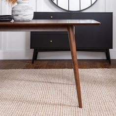 a wooden table sitting in front of a round mirror on top of a white wall