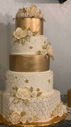 a three tiered wedding cake with white and gold flowers