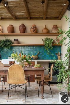 a dining room table with chairs and vases on the shelves above it, along with potted plants