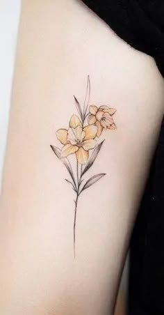 a small yellow flower tattoo on the back of a woman's arm