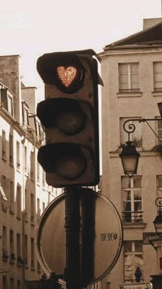 a traffic light with a heart on it in the middle of an urban area,