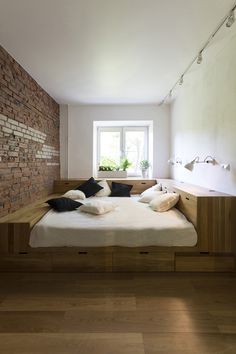 a bed that is in the middle of a room next to a brick wall and wooden floor