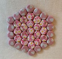 a pink and white flowered button with hearts on it