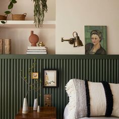 a bedroom with green striped walls and white bedding, potted plants on the shelf