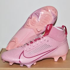 a pair of pink nike soccer cleats sitting on top of a cardboard box