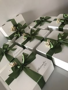 many white boxes with green bows and pearls