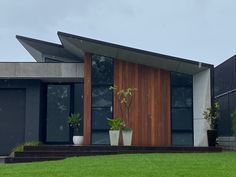 a house with two plants in front of it and grass on the ground next to it