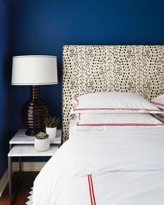 a bedroom with blue walls and white bedding