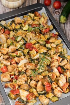 a tray filled with chicken and vegetables on top of a wooden table