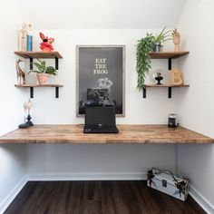 a laptop computer sitting on top of a wooden desk next to shelves filled with plants