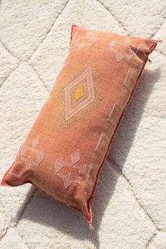 an orange pillow sitting on top of a white rug