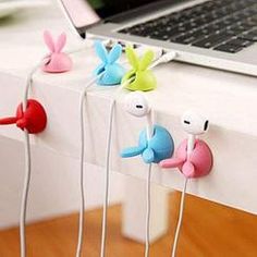 four colorful bunny ear buds are on the table next to a laptop