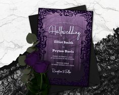 a purple and black wedding card with a rose in it on top of some lace