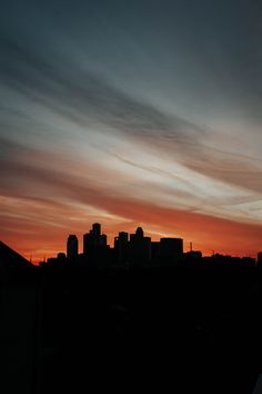 the sun is setting over a city with skyscrapers in the background and clouds in the sky