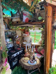 an outdoor kitchen with lots of plants and decorations on the shelves, including candles, plates and bowls