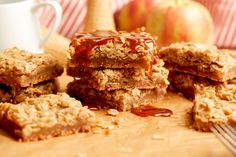 apple pie bars stacked on top of each other with caramel sauce drizzled over them