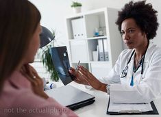 a doctor talking to a patient in an office setting on her laptop computer while sitting at a desk