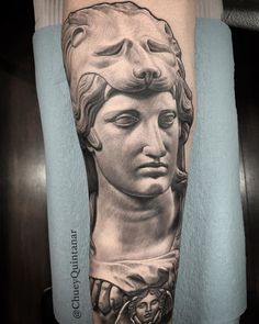 a man's leg with a tattoo on it that has an image of a statue