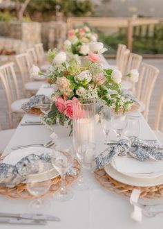 the table is set with white and blue plates, silverware, and flowers in vases