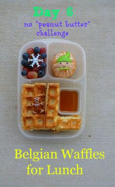 a plastic container filled with waffles and fruit on top of a white table