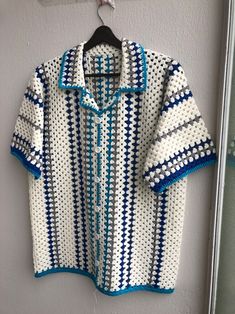 a crocheted shirt hanging on a wall