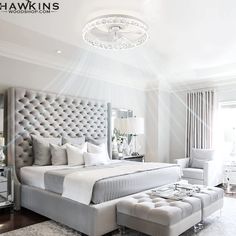 a bedroom with a large bed, white furniture and a chandelier hanging from the ceiling