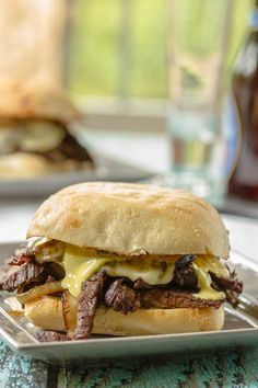 a steak sandwich on a plate with cheese