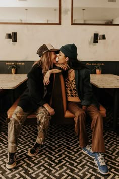 two people sitting on a bench in a restaurant, one kissing the other's cheek