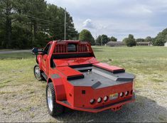 a red truck parked on top of a grass covered field