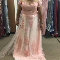 a woman standing in front of a mirror wearing a pink dress