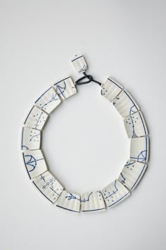 a white and blue bracelet with writing on the inside of it, hanging from a hook