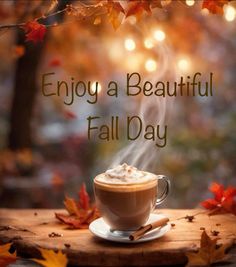 a cup of coffee sitting on top of a wooden table with autumn leaves around it