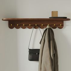 a coat rack with two coats hanging from it's hooks and a purse on the wall