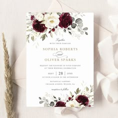 an elegant burgundy and white wedding card with flowers on it