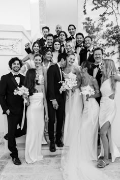 a group of people standing next to each other in front of a staircase with flowers