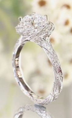 a close up view of a diamond ring with flowers in the background