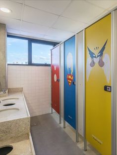 three bathroom stalls with superman and wonder symbols painted on the doors next to each other