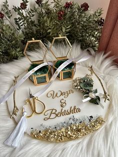 two wedding rings and some jewelry on top of a white furnishing with greenery in the background