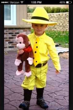 a little boy dressed up as a fireman with a monkey in his hand and wearing a yellow hat