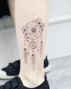 a woman's leg with a tattoo on it that has an image of a dream catcher