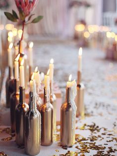 there are many bottles with candles in them on the table