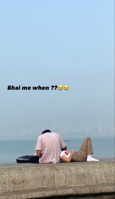 two people sitting on the edge of a pier looking out at the water and one person is reading a book